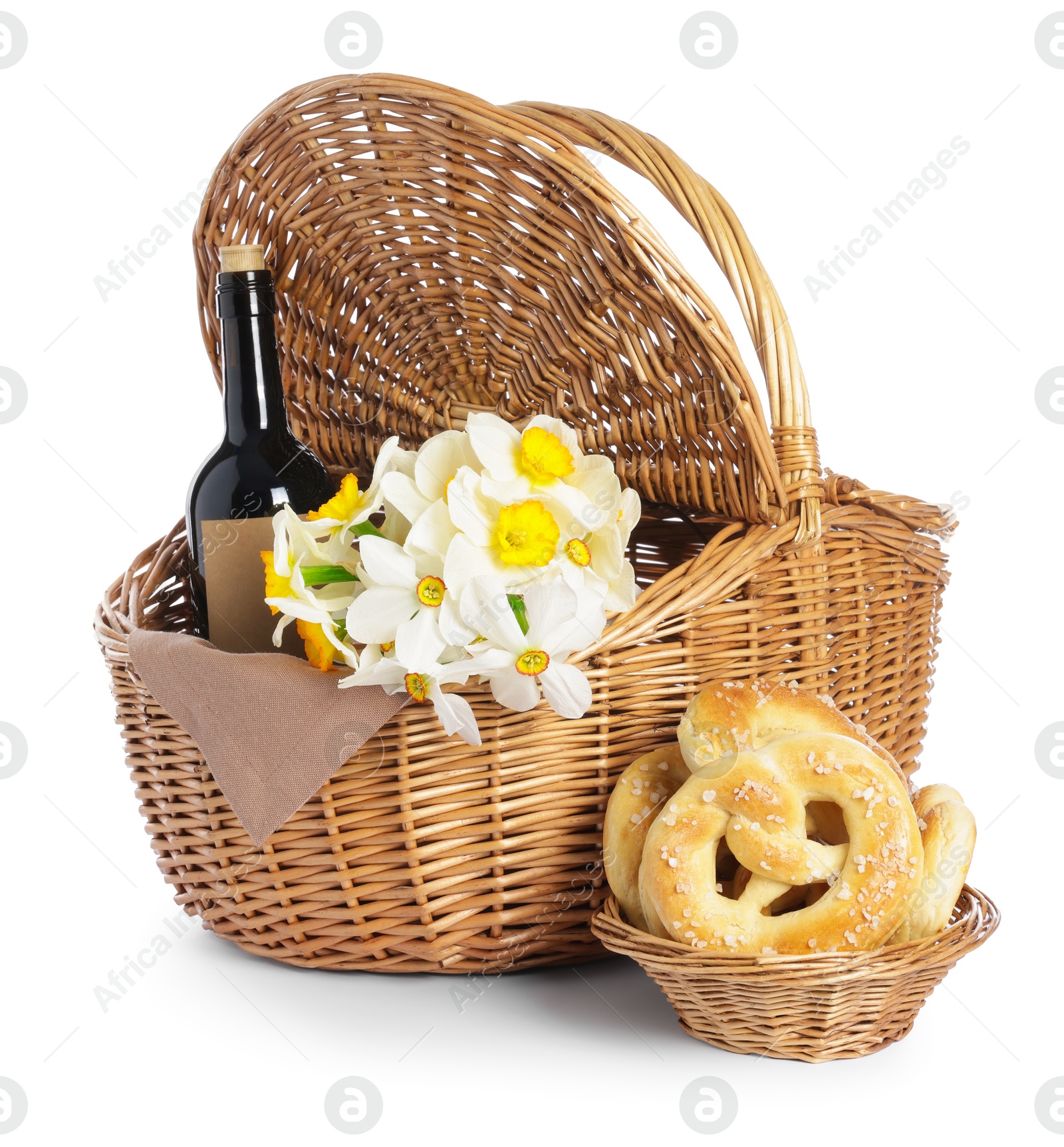 Picnic wicker basket with beautiful flowers, bottle of wine and pretzels isolated on white Photo of Picnic wicker basket with beautiful flowers, bottle of wine and pretzels isolated on white