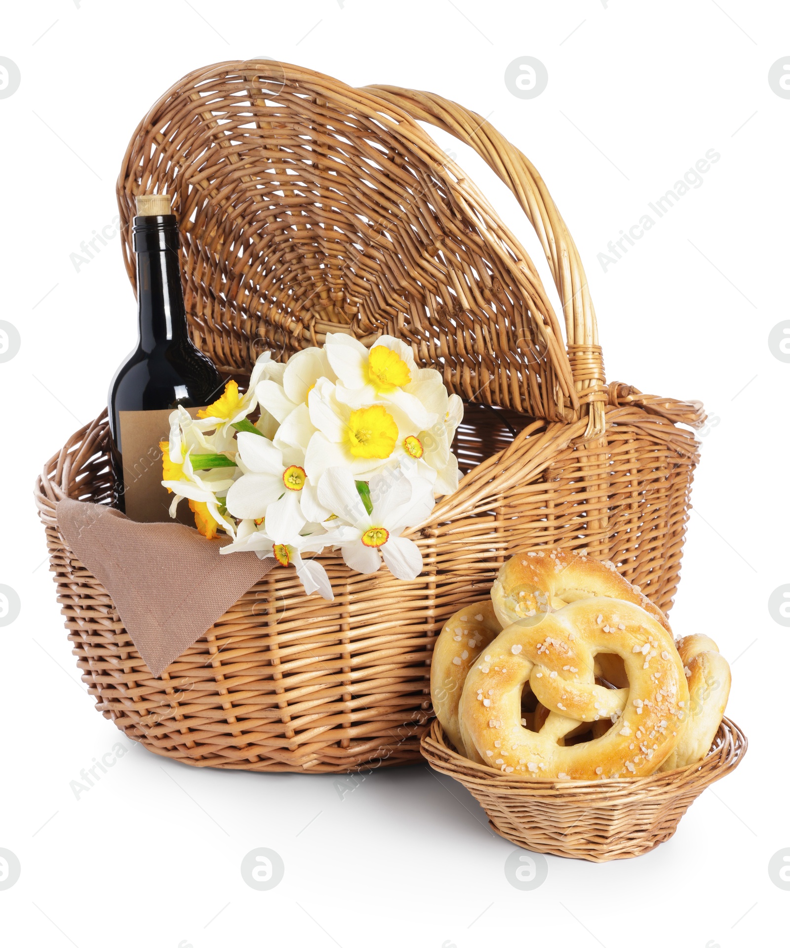 Picnic wicker basket with beautiful flowers, bottle of wine and pretzels isolated on white Photo of Picnic wicker basket with beautiful flowers, bottle of wine and pretzels isolated on white