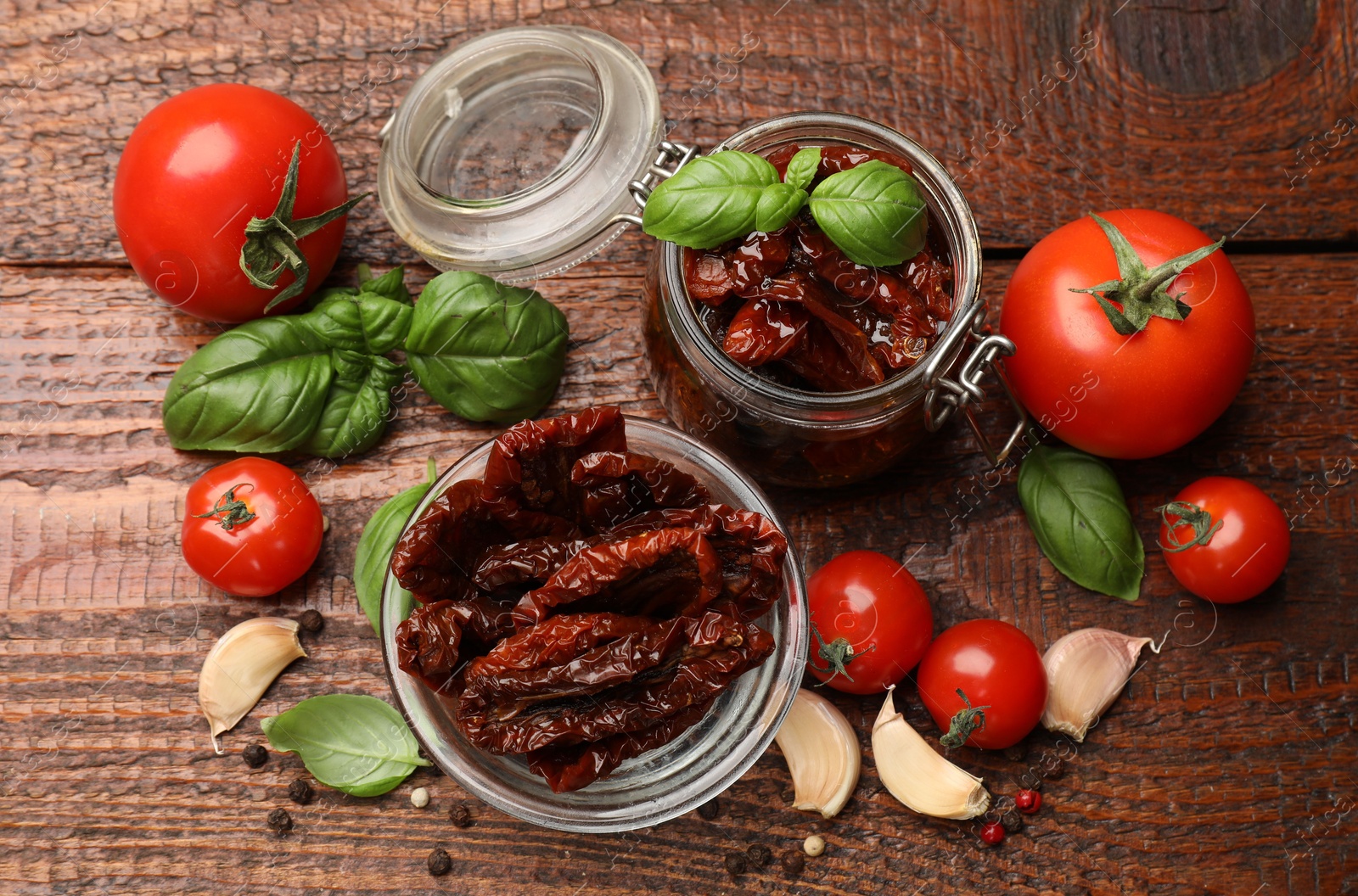 Delicious sun dried tomatoes in glass dishware, fresh vegetables and spices on wooden table, flat lay Photo of Delicious sun dried tomatoes in glass dishware, fresh vegetables and spices on wooden table, flat lay