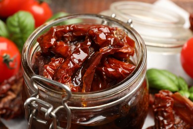 Photo of Delicious sun dried tomatoes in glass jar on table, closeup