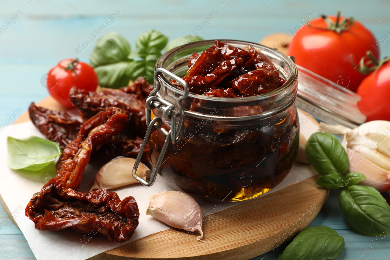 Delicious sun dried tomatoes in glass jar, fresh vegetables and spices on light blue table, closeup Photo of Delicious sun dried tomatoes in glass jar, fresh vegetables and spices on light blue table, closeup