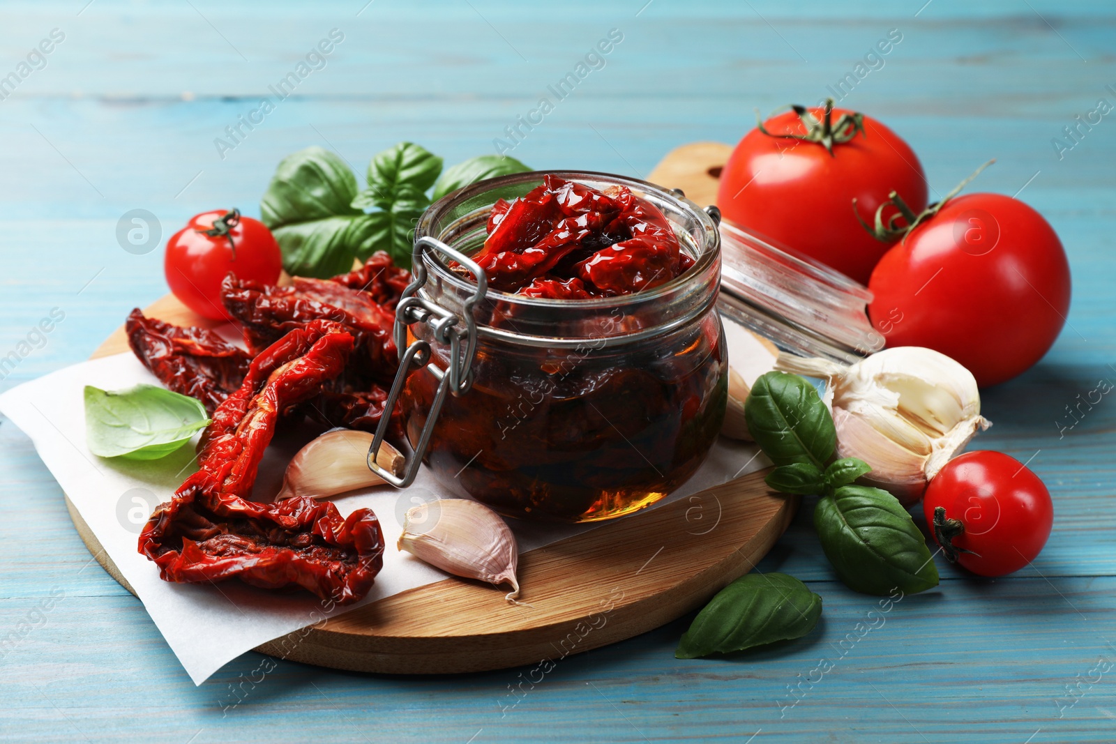 Delicious sun dried tomatoes in glass jar, fresh vegetables and spices on light blue wooden table, closeup Photo of Delicious sun dried tomatoes in glass jar, fresh vegetables and spices on light blue wooden table, closeup