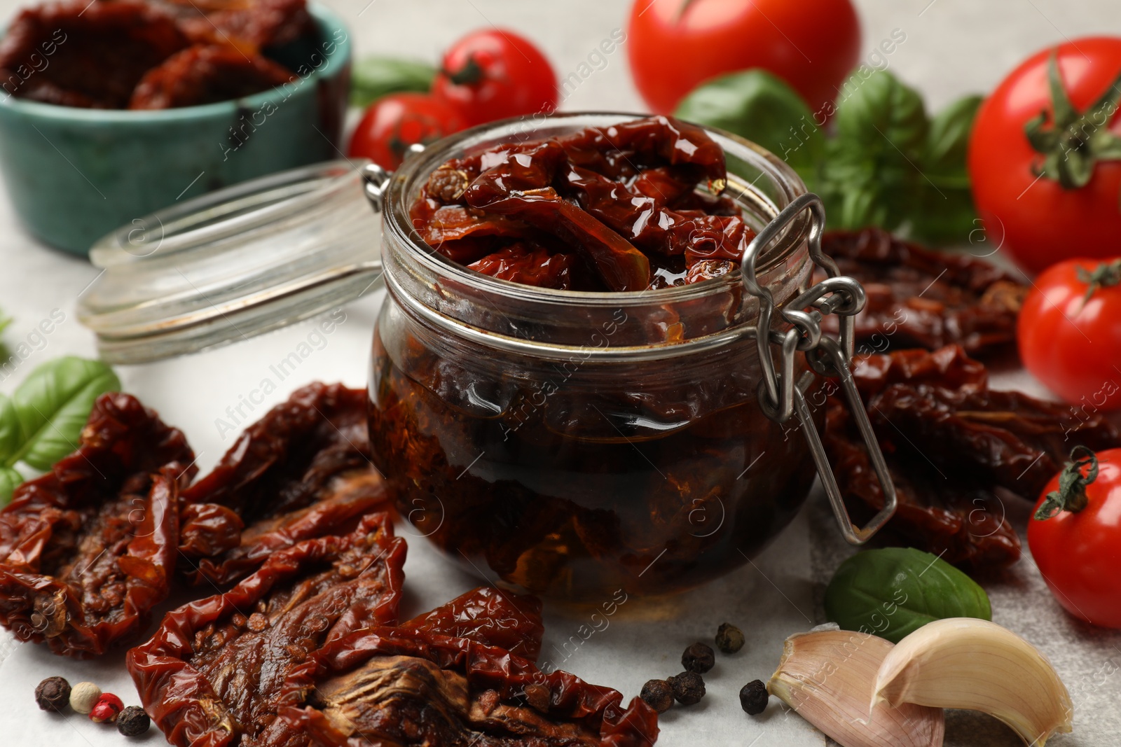 Delicious sun dried tomatoes in glass jar, fresh vegetables and spices on gray table, closeup Photo of Delicious sun dried tomatoes in glass jar, fresh vegetables and spices on gray table, closeup