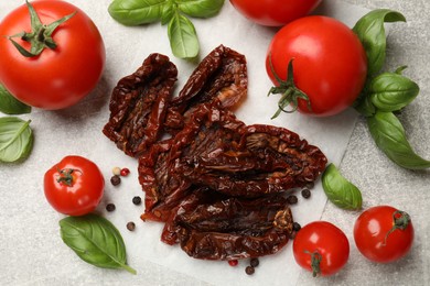 Photo of Delicious sun dried tomatoes, fresh vegetables and spices on gray textured table, flat lay