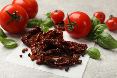 Photo of Delicious sun dried tomatoes, fresh vegetables and spices on gray textured table, closeup