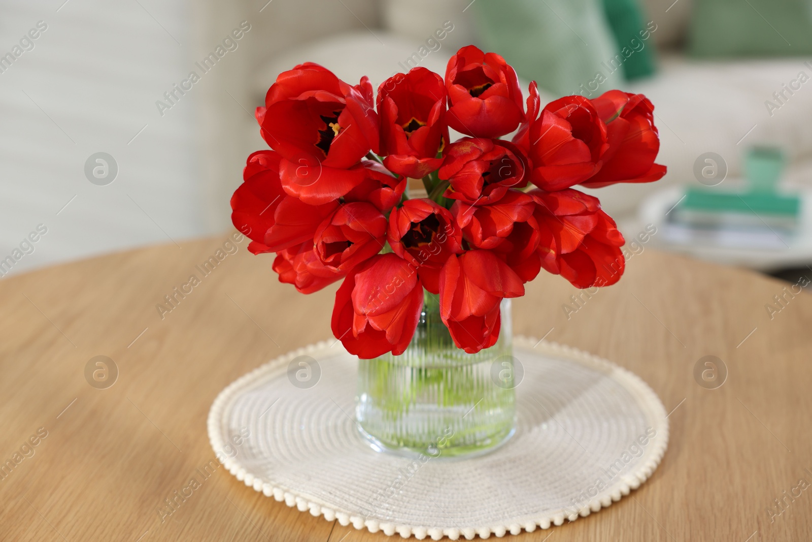 Photo of Beautiful red tulips in vase on wooden table indoors, closeup
