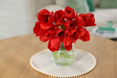 Photo of Beautiful red tulips in vase on wooden table indoors, closeup