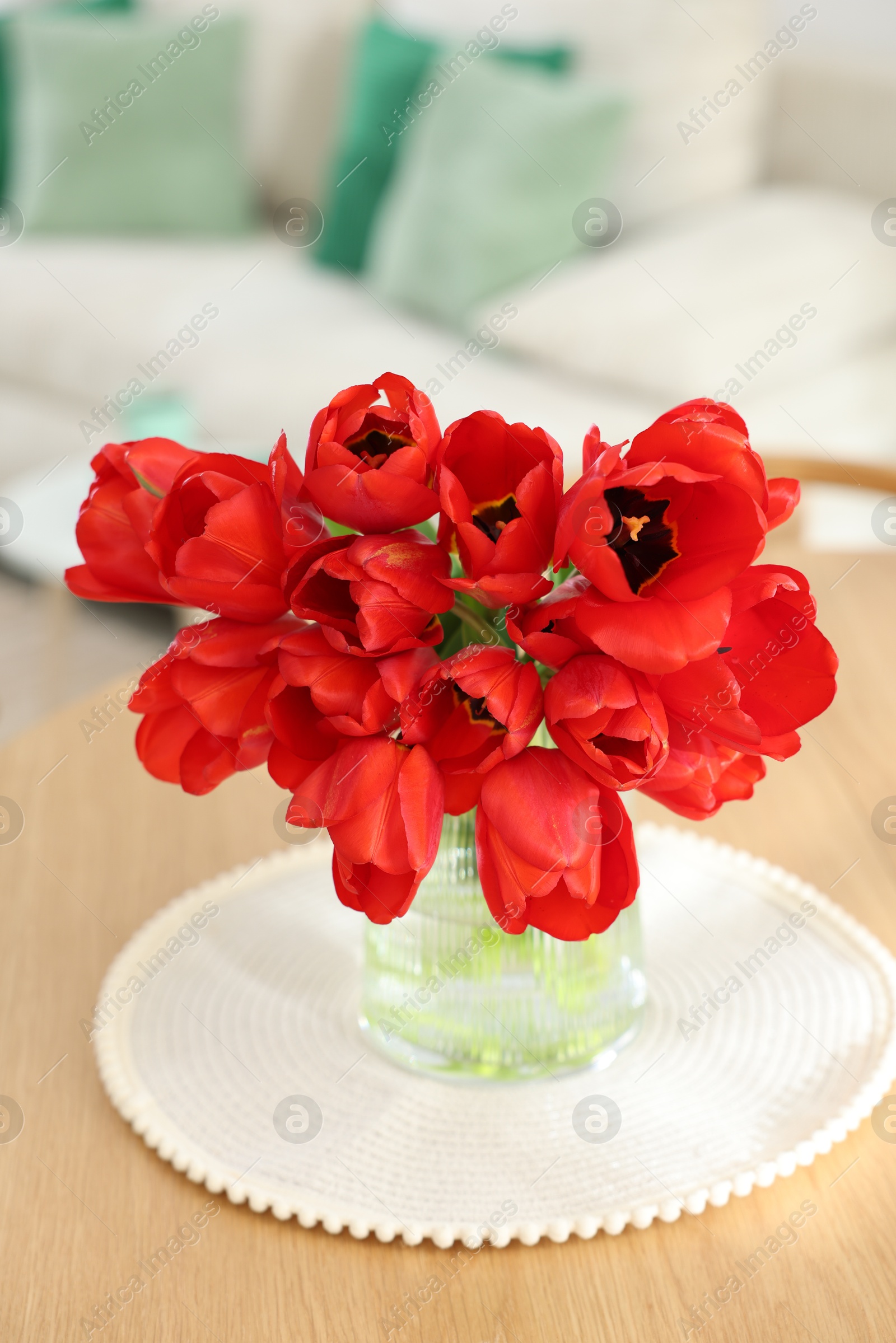Photo of Beautiful red tulips in vase on wooden table indoors, closeup