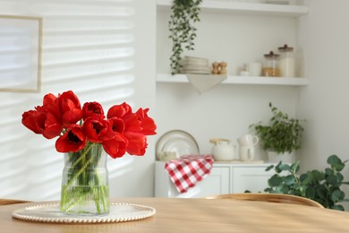 Photo of Beautiful red tulips in vase on wooden table indoors, space for text