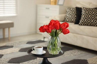 Photo of Beautiful red tulips in vase and tea on table indoors