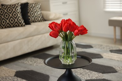 Photo of Beautiful red tulips in vase on table indoors, space for text