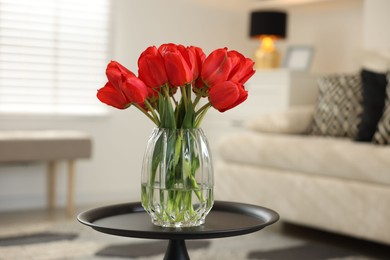 Photo of Beautiful red tulips in vase on table indoors