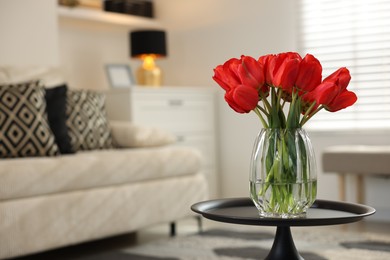 Photo of Beautiful red tulips in vase on table indoors, space for text