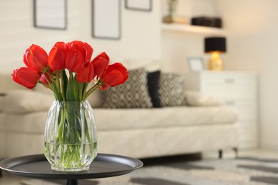 Photo of Beautiful red tulips in vase on table indoors, space for text