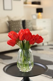 Photo of Beautiful red tulips in vase on table indoors
