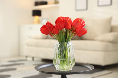 Photo of Beautiful red tulips in vase on table indoors