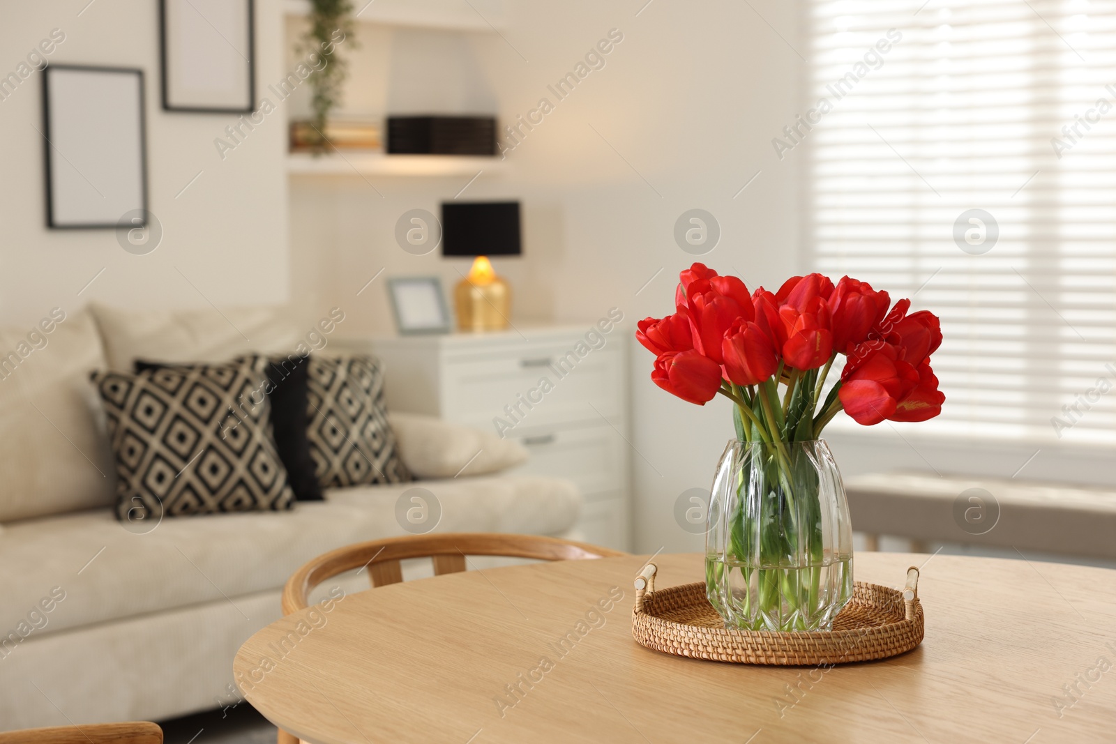 Beautiful red tulips in vase on wooden table indoors, space for text Photo of Beautiful red tulips in vase on wooden table indoors, space for text