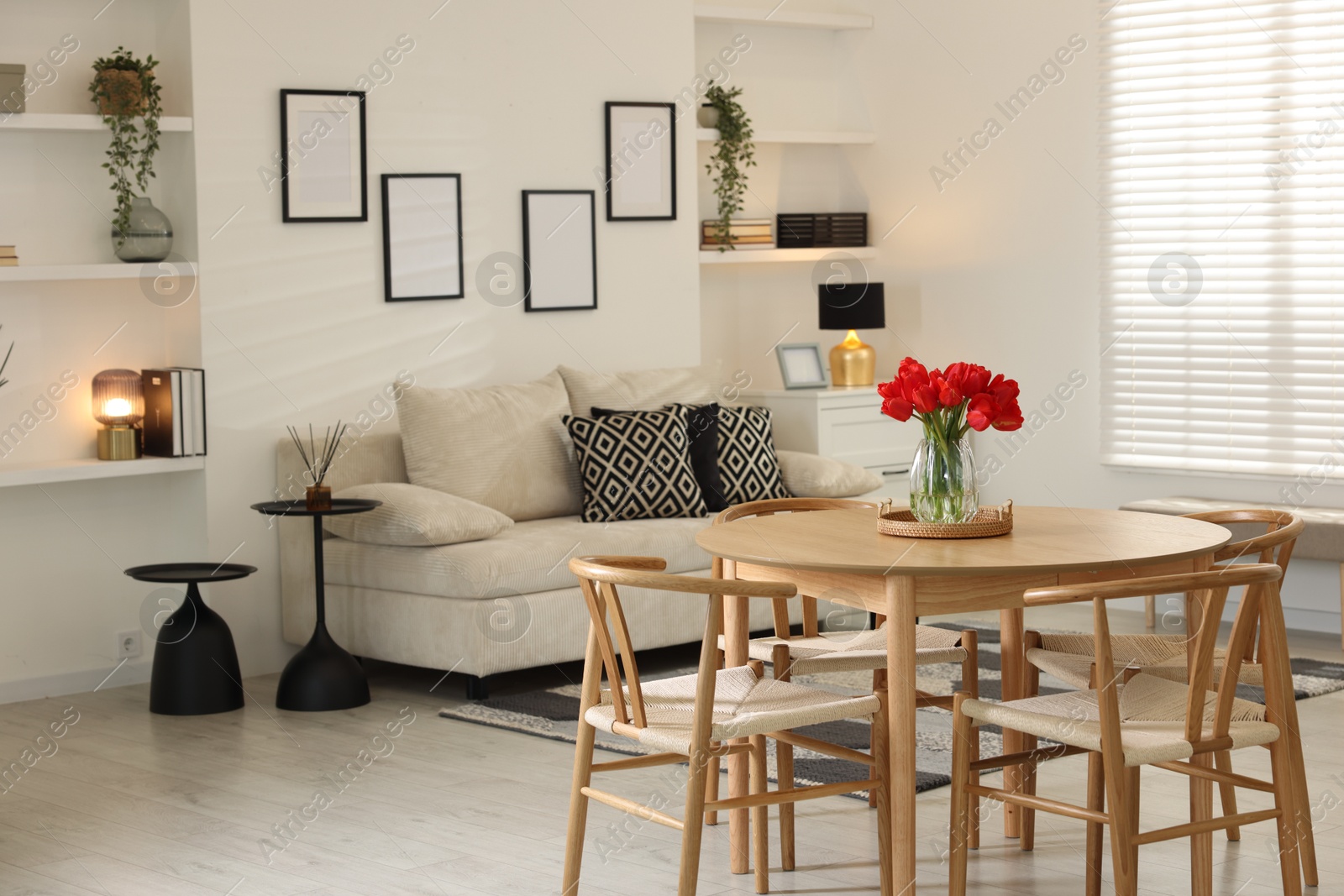 Photo of Beautiful red tulips in vase on wooden table indoors, space for text