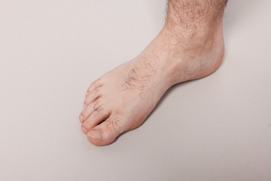 Photo of Barefoot man on light grey background, closeup