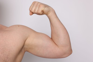 Photo of Man showing his bicep on light background, closeup