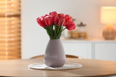 Photo of Beautiful tulips in vase on wooden table indoors