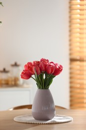 Photo of Beautiful tulips in vase on wooden table indoors. Space for text