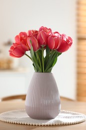 Photo of Beautiful tulips in vase on wooden table indoors