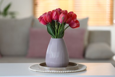 Photo of Beautiful tulips in vase on white table indoors