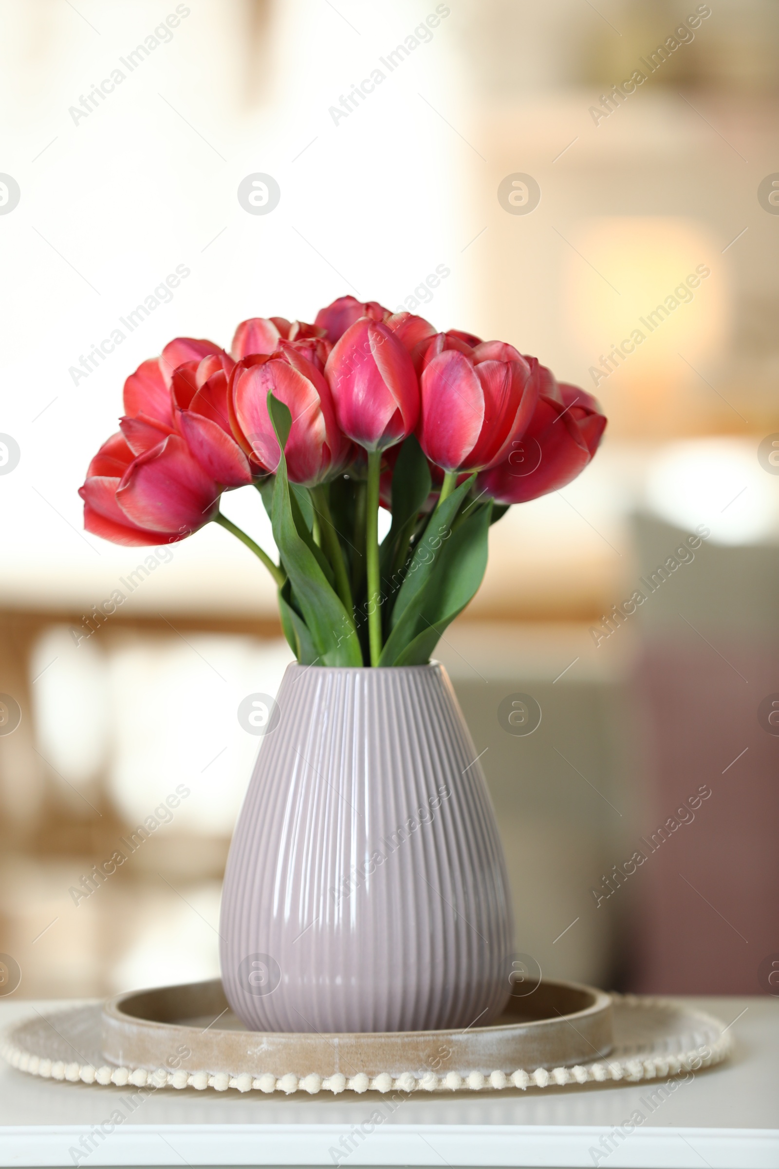 Photo of Beautiful tulips in vase on white table indoors