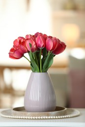 Photo of Beautiful tulips in vase on white table indoors