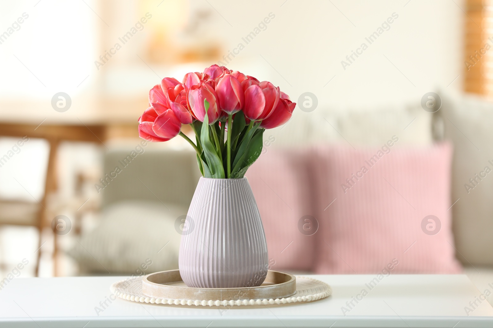 Photo of Beautiful tulips in vase on white table indoors