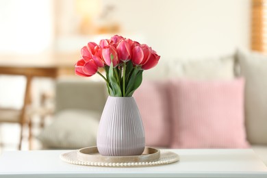 Photo of Beautiful tulips in vase on white table indoors