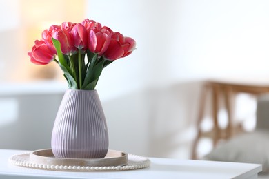 Photo of Beautiful tulips in vase on white table indoors. Space for text