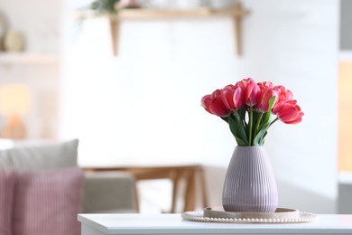 Photo of Beautiful tulips in vase on white table indoors. Space for text
