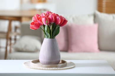 Photo of Beautiful tulips in vase on white table indoors