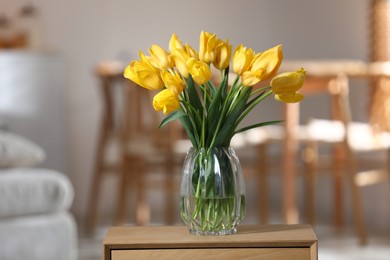 Photo of Beautiful tulips in vase on wooden table indoors