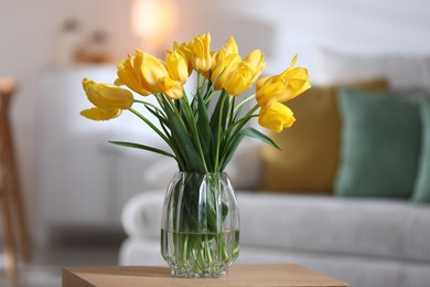 Photo of Beautiful tulips in vase on wooden table indoors
