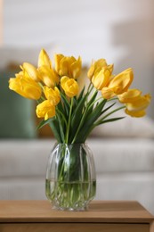 Photo of Beautiful tulips in vase on wooden table indoors