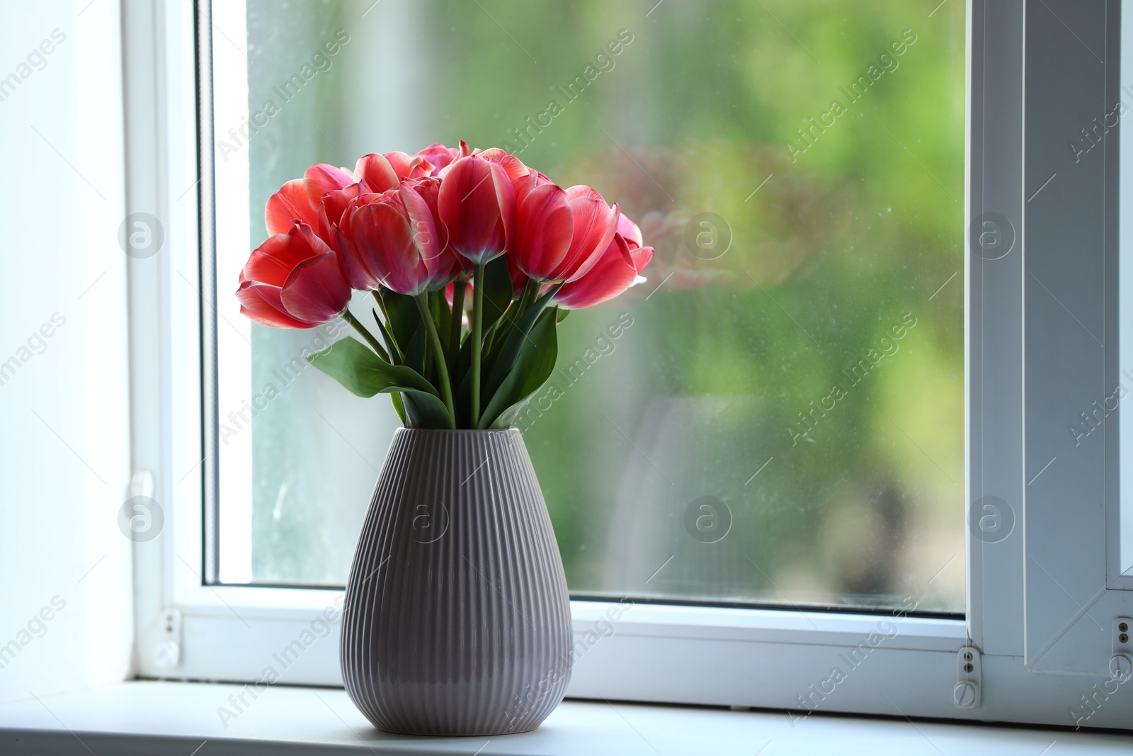 Photo of Beautiful tulips in vase on window sill. Space for text