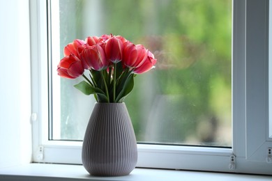 Photo of Beautiful tulips in vase on window sill. Space for text