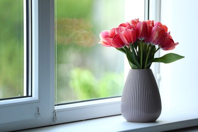 Photo of Beautiful tulips in vase on window sill. Space for text