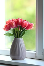 Photo of Beautiful tulips in vase on window sill