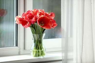Photo of Beautiful tulips in vase on window sill