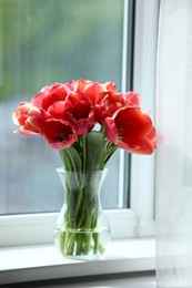 Photo of Beautiful tulips in vase on window sill