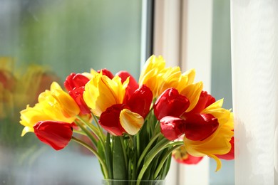 Photo of Beautiful colorful tulips near window indoors, closeup