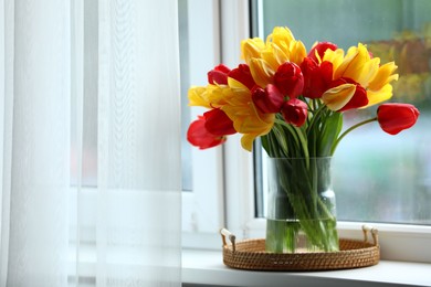 Photo of Beautiful tulips in vase on window sill