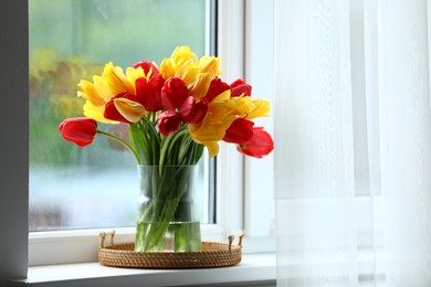 Photo of Beautiful tulips in vase on window sill