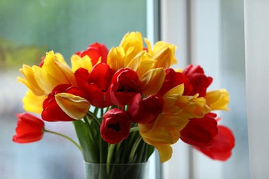 Photo of Beautiful colorful tulips near window indoors, closeup