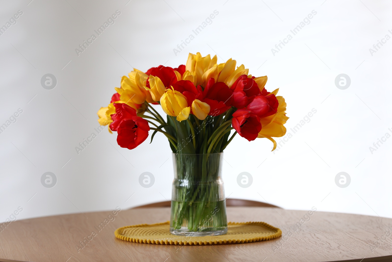 Photo of Beautiful tulips in vase on wooden table indoors