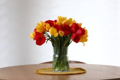 Photo of Beautiful tulips in vase on wooden table indoors